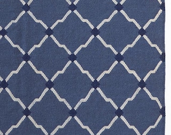 May include: A blue rug with a repeating diamond pattern. The diamonds are formed by a light gray wavy line that intersects with a darker blue square in the center of each diamond. The rug has a textured appearance.