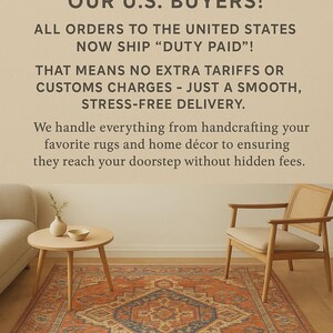 May include: An orange and blue patterned rug is the focal point of a living room scene. The room includes a wooden side table with a vase and bowl, a beige sofa, and a wooden chair. Text in the image reads "HEMANT HANDICRAFTS" and "GOOD NEWS FOR OUR U.S. BUYERS!"