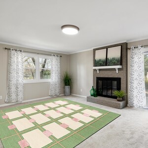 May include: A living room with a green and cream-colored rug, a fireplace, and a window with white curtains. The rug has a geometric pattern with rectangular cream-colored shapes and pink accents. The fireplace is brick with a black firebox.