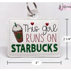 May include: White leather keychain with green and red embroidery that reads "This girl runs on Starbucks" with a cartoon image of a coffee cup. The keychain measures 3 inches wide and 2 1/4 inches tall.