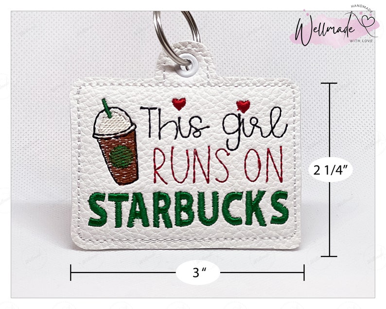 May include: White leather keychain with green and red embroidery that reads "This girl runs on Starbucks" with a cartoon image of a coffee cup. The keychain measures 3 inches wide and 2 1/4 inches tall.