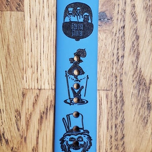 May include: A blue Apple Watch band with a black design featuring the text "Beware of Hitchhiking Ghosts" and images of characters from the Haunted Mansion attraction.