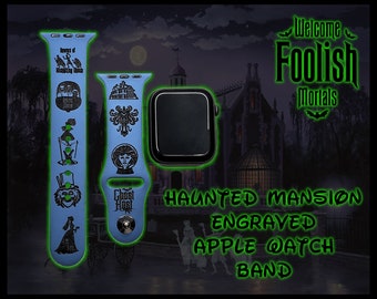 May include: A blue Apple Watch band with an engraved design featuring characters and imagery from the Haunted Mansion attraction at Disneyland. The band features the text "Ghost Host" and "Welcome Foolish Mortals". The text "Haunted Mansion Engraved Apple Watch Band" is displayed in green.