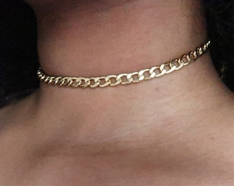 May include: A gold chain choker necklace.