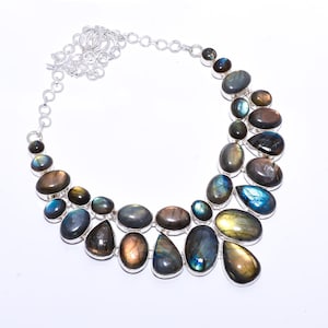 Op de afbeelding: Een zilveren ketting met een hanger van labradoriet. De hanger is gemaakt van meerdere druppelvormige stenen in tinten blauw, groen en goud.