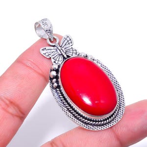 Puede incluir: Pendiente de plata con una piedra de coral rojo y un diseño de mariposa.