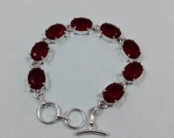 Puede incluir: Pulsera de plata con piedras preciosas ovaladas de color rojo intenso. Las piedras están engastadas individualmente en engastes de plata y conectadas por eslabones de plata. Cierre de palanca. Una joya.