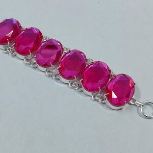 Può includere: Un bracciale in argento con sei pietre preziose rosa ovali e vibranti. Le pietre sono incastonate in castoni individuali in argento e collegate da una delicata catena d'argento. Chiusura a toggle.
