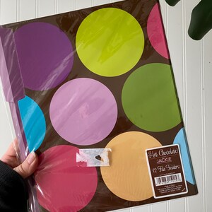 May include: A pack of 12 file folders in a brown base color featuring large, colorful polka dots in shades of lime green, purple, light pink, dark pink, orange, and blue. A rectangular label on the front reads Hot Chocolate! JACKIE 12 File Folders.
