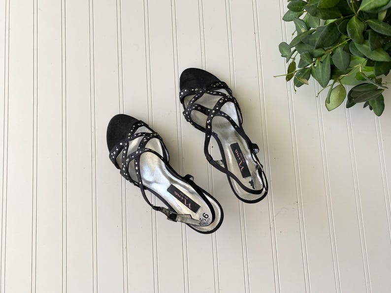 K&ouml;nnte beinhalten: Paar schwarze Sandalen mit Riemchen und silbernen Akzenten. Die Sandalen haben einen Slingback-Riemen und sind mit kleinen silbernen Nieten verziert. Die Sohlen sind silberfarben, und die Schuhe sind Gr&ouml;&szlig;e 9.