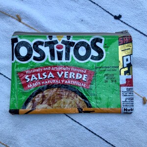 May include: Green and white zippered pouch made from a repurposed Tostitos Salsa Verde bag. The pouch features the Tostitos logo and text "SALSA VERDE" in red. The pouch has a silver zipper and a printed expiration date.
