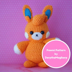 Op de afbeelding: Een gehaakt oranje Pawmi knuffel met blauwe oren en witte accenten. Het speelgoed zit op een roze achtergrond met witte stippen. De tekst "Pawmi Pattern by DerptheMagikerp" staat op een roze cirkel.