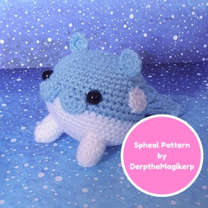 May include: A crocheted blue and white whale plushie with black eyes. The plushie is sitting on a blue background with white dots. The text "Spheal Pattern by DerptheMagikerp" is on a pink circle.