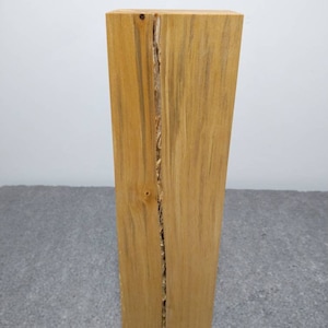 Könnte beinhalten: Ein hoher, rechteckiger Holzblock in natürlicher, hellbrauner Farbe. Das Holz hat einen langen, dünnen Riss, der durch die Mitte verläuft.