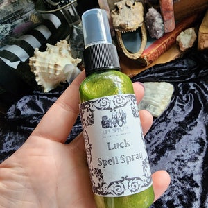 May include: A green glass bottle with a black spray top and a white label that reads "Life Spirits" and "Luck Spell Spray".