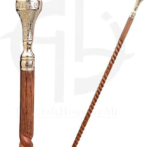 May include: A walking stick featuring a brown wooden shaft with a twisted design and a polished gold-tone metal handle. The handle has an ornate, engraved leaf pattern and a smooth, rounded top. The shaft connects to the handle with a smooth metal collar.