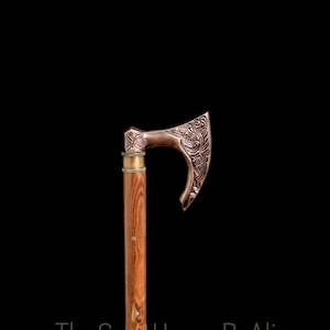 May include: A wooden walking stick with a brass axe head. The axe head has an intricate design.