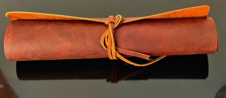 May include: A rolled-up piece of brown leather with a tan leather strap tied around it.