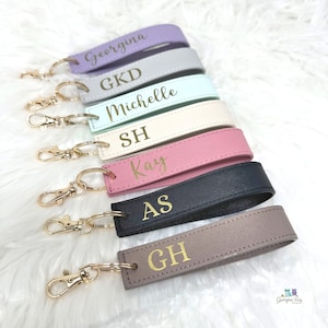 May include: Seven colourful leather keychains with gold key rings and personalised names in gold lettering. The names are Georgina, GKD, Michelle, SH, Kay, AS, and CH.