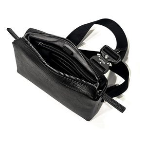 Puede incluir: Bolso bandolera de cuero negro con cremallera abierta que revela bolsillos interiores. El bolso tiene una correa negra y un cierre metálico con la palabra "MIROS" impresa. El bolso es rectangular y tiene una superficie texturizada.