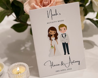 May include: A white card with black text that reads "Noah's Activity Book".  The card features a cartoon illustration of a bride and groom. The bride is wearing a white dress and the groom is wearing a black tuxedo. The text below the illustration reads "Flavia & Antony 2ND APRIL 2022".