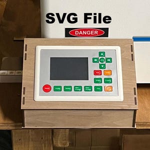 May include: A wooden control panel with a digital display and various buttons. The panel is labeled with the text "SVG File" and "DANGER". The buttons are red, green, and orange. The panel is likely for a laser cutter or similar machine.