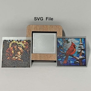 May include: A wooden picture frame with a silver insert, flanked by two square images. One image depicts the Holy Family, the other a red cardinal bird on a snowy branch. The text "SVG File" is above the frame.