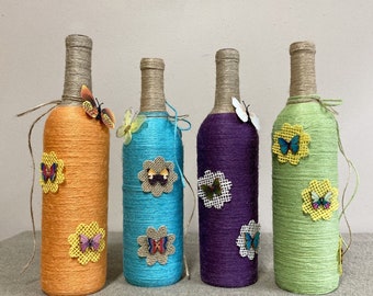 Jute Wrapped and decorated wine bottle decor.  Each bottle has a different color jute and decoration. Many assorted colors available.