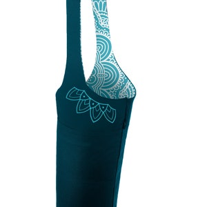 May include: A teal blue yoga mat bag with a white and teal patterned lining. The bag has a single strap and a small pocket on the side.
