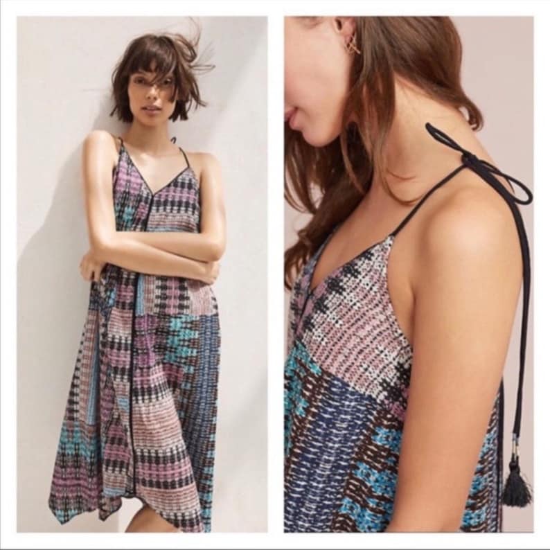 May include: A sleeveless midi dress with a geometric pattern in shades of blue, pink, and black. The dress has a V-neckline and adjustable straps with tassels.