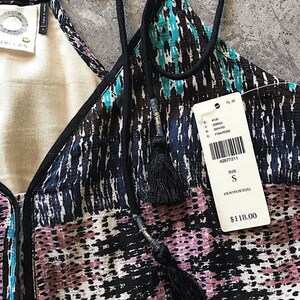 May include: A black and blue patterned sleeveless top with a black trim and tassel ties. The tag reads "Size S (Also in Petite)" and "$118.00".