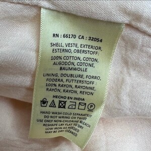May include: A beige garment care label with the text "RN: 66170 CA: 32054" and care instructions for hand washing cold separately, do not wring or twist, use only non-chlorine bleach, reshape lay flat to dry, low iron as needed, may be dry cleaned. The label also includes the text "HECHO EN INDIA".