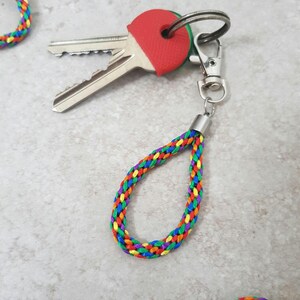 May include: A rainbow braided key chain with a silver key ring and a red key cap.