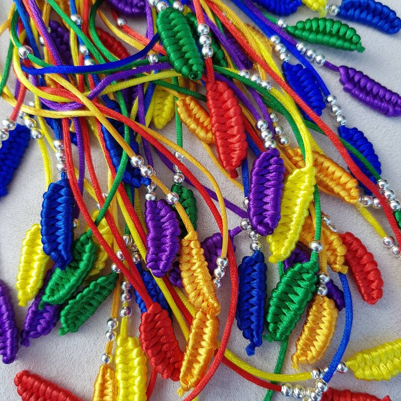 May include: A collection of colorful, braided, leaf-shaped charms with silver beads. The charms are made of various colors, including red, orange, yellow, green, blue, and purple.