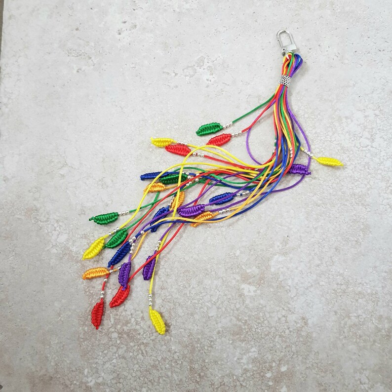 May include: A rainbow-colored keychain with a silver clasp and multiple strands of string with small, colorful leaf-shaped beads.