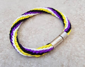 May include: A braided bracelet with yellow, white and purple stripes and a silver magnetic clasp.