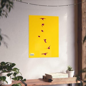 Puede incluir: Un póster amarillo con una serie de pájaros púrpuras estilizados en vuelo. Las aves están dispuestas en una línea vertical sobre el fondo amarillo. Un pequeño logotipo es visible en la esquina inferior izquierda.