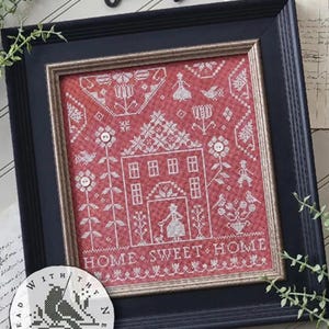 Könnte beinhalten: Gerahmte Kreuzstichkunst mit rotem Hintergrund und weißen Stichen. Das Design zeigt ein Haus, Blumen, Vögel und den Text "HOME SWEET HOME". Der Rahmen ist schwarz.