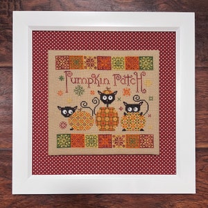 Könnte beinhalten: Ein gerahmtes Kreuzstich-Design mit drei schwarzen Katzen, die auf Kürbissen sitzen. Das Design trägt den Titel "Pumpkin Patch" und ist von einem roten und weißen Tupfenrand umgeben.