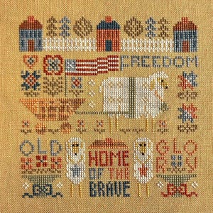 May include: Cross-stitch sampler with a patriotic theme. It features a white sheep, red, white, and blue houses, a banner with the word "FREEDOM", and the text "OLD HOME OF THE BRAVE".