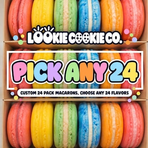 May include: A cardboard box containing rows of colorful macarons in pink, yellow, green, blue, and orange. The text reads LOOKIE COOKIE CO. PICK ANY 24 CUSTOM 24 PACK MACARONS, CHOOSE ANY 24 FLAVORS. The macarons are arranged in three horizontal rows.