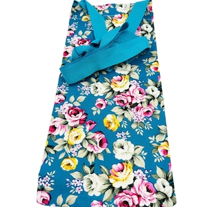 May include: A turquoise blue tote bag with a floral print featuring pink, yellow, and white roses. The bag has turquoise blue straps.