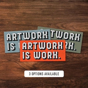 May include: Three rectangular art prints with the text "ARTWORK IS WORK" in a bold, vintage font. The prints are in shades of orange, blue-gray, and olive green. The phrase "3 OPTIONS AVAILABLE" is also visible.
