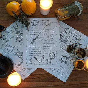 May include: Three printable sheets of paper with handwritten herbal recipes for a calming herbal tea, a home cleanser, and a green tea honey face wash. The recipes are illustrated with drawings of a teacup, a broom, and a bathtub. The sheets are on a wooden table with candles, oranges, and a jar of herbs.