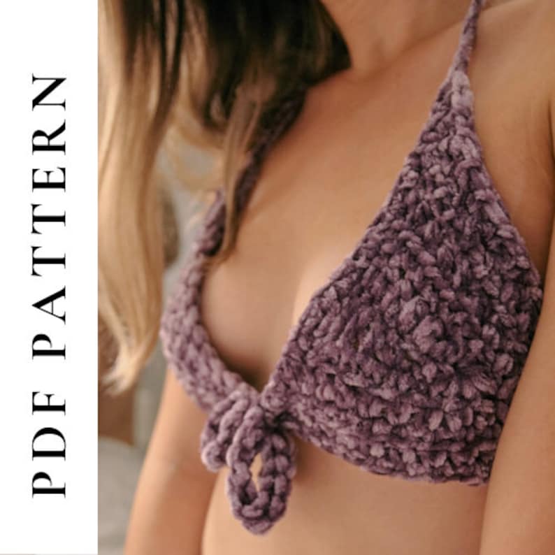 May include: A purple crocheted bralette with a tie front detail. The bralette is made of a soft, fuzzy yarn.