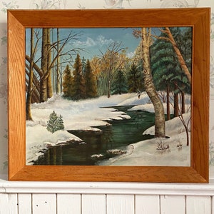 May include: A framed painting of a winter scene with a winding stream through a snowy forest. The trees are bare and the sky is blue with white clouds. The painting is signed "H. Taylor" in the lower left corner.