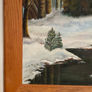May include: A framed painting of a winter scene with a small evergreen tree in the foreground and a snow-covered forest in the background. The painting is signed "E.M. Taylor" in the lower right corner.