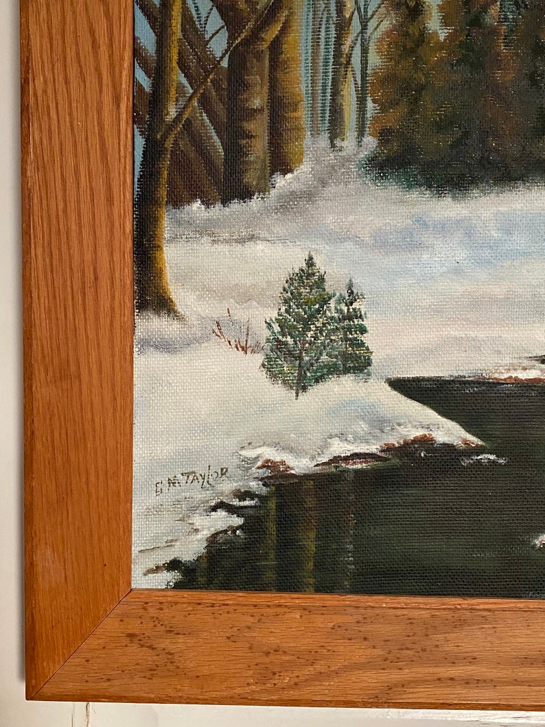 May include: A framed painting of a winter scene with a small evergreen tree in the foreground and a snow-covered forest in the background. The painting is signed "E.M. Taylor" in the lower right corner.