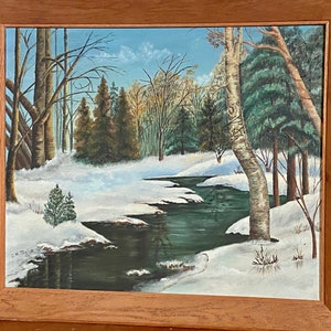 May include: A painting of a winter scene with a winding stream flowing through a snowy forest. The trees are bare and the ground is covered in white snow. The stream is a deep green color and reflects the blue sky above. The painting is framed in a wooden frame.