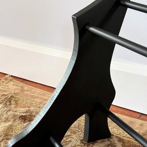 Peut inclure: Un pr&eacute;sentoir &agrave; chaussures en bois noir avec un design incurv&eacute;. Le pr&eacute;sentoir comporte trois barres horizontales pour ranger les chaussures et un panneau lat&eacute;ral incurv&eacute; d&eacute;coratif. Le pr&eacute;sentoir est en bois et peint en noir.